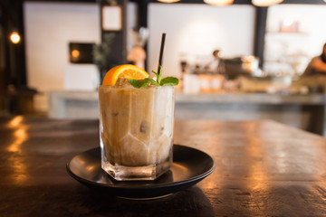 Citrus fresh and vanilla syrup blended iced coffee in glass on dark wooden table.