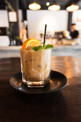 Citrus fresh and vanilla syrup blended iced coffee in glass on dark wooden table.