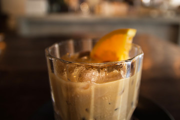 Citrus fresh and vanilla syrup blended iced coffee in glass on dark wooden table.
