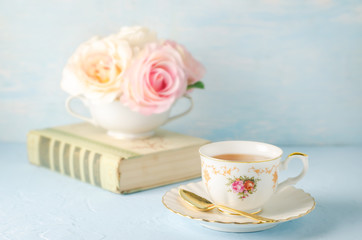 Close up of cup of tea with flowers and book on blue background with vintage tone