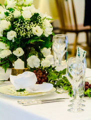 Christmas party dinner table setting with tableware and silverware and glasses set and Candlestick and flower in restaurant.