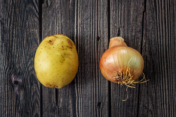 Close-up of unpeeled potato and  onion on wooden dark background. Harvest, vegetables.