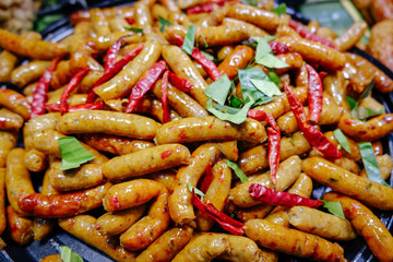 Northern Thai spicy herbal sausages freshly cooked in a pan for sale in local market, Thailand. Ready to eat street food.