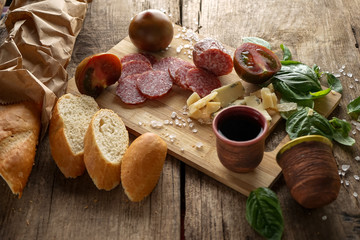 sausage cut on a cutting board with baguette and decor on an old wooden background