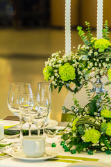Wedding party dinner table setting with tableware and silverware and glasses set and Candlestick and flower in restaurant.