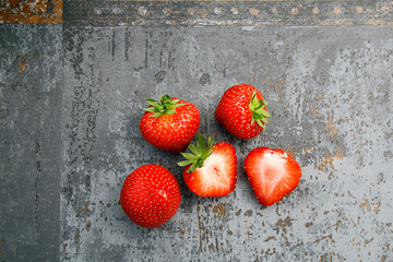 Five Strawbwerries - fresh ripe Strawberries flat laid on a rustic kitchen counter. 