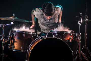 Fototapeta na wymiar musician playing drums with splashes, black background with beautiful soft light