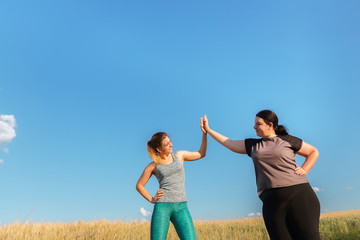 Motivation, group workout, weight loss. Two happy women friends give a five after jogging. Sports and health care