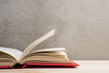 Education and reading concept - group of colorful books on the wooden table, concrete wall blackboard