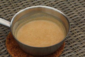 Pan with peanut sauce on wooden background