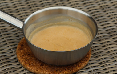 Pan with peanut sauce on wooden background