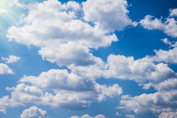 Obraz premium Background of blue sky, white clouds and sun rays coming through the heaven