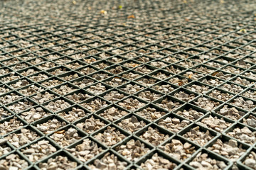 special pavement of metal mesh and small gravel for arranging parking space. Diamond-shaped structure with crushed stone.