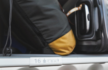 Detail on seat and rows CBA sign inside the airplane, overhead locker with blurred baggage above
