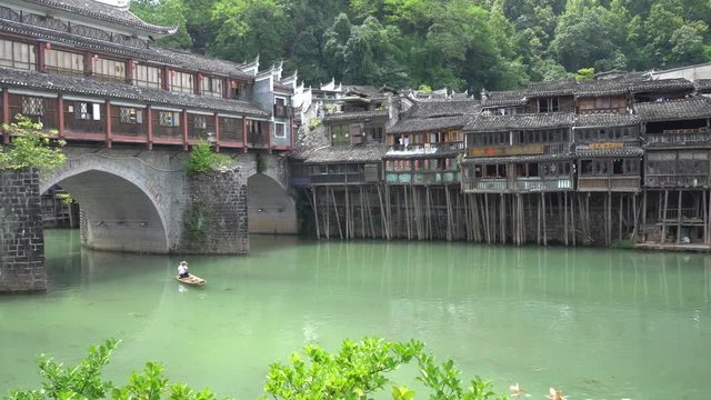 Traditional wooden boats full on Tuojiang river and old traditional houses on riverside in Fenghuang phoenix town in Hunan, China