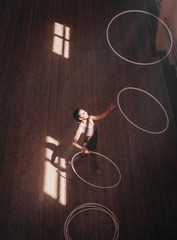 woman performs with several hoops in gymnasium. top view