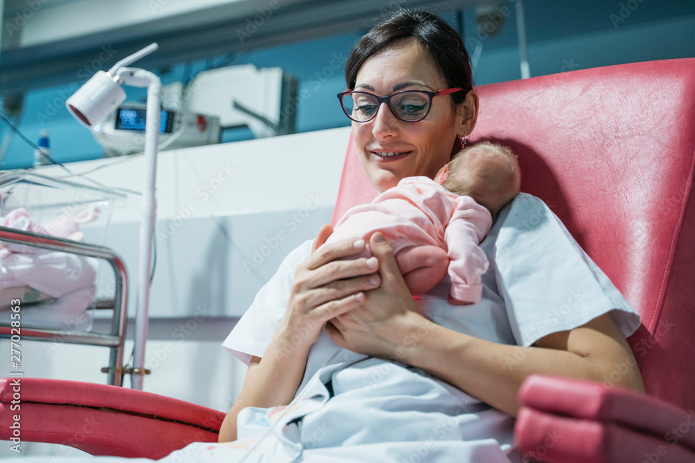 Wall mural female doctor examining newborn baby after lunch. night shift