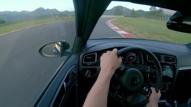 CLOSE UP: Man wearing a helmet races his fast car along the fun racetrack. Unrecognizable adrenaline seeking male race car driver having fun by driving his awesome sportscar along a closed track.