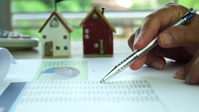 Businessman signature in loan graph document home on mortgage real estate report, checking documents contract in property investment in architectural project on desk office in documents. House focus