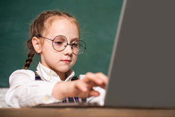 Pupil girl working on a laptop. Cute little preschool kid boy study in a classroom. Educational process. Elementary school and education.