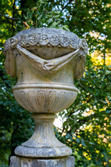 Garden decorative decoration among the greenery, an ancient granite vase stands on a pedestal in the Park