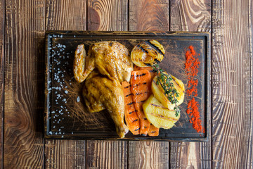 Grilled chicken and vegetables on a wooden table.