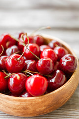 Red ripe cherry berries in wooden bowl. Food background