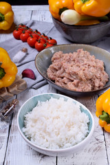 Boiled rice, raw pork and beef mince and yellow bell peppers. Ingredients for making stuffed peppers