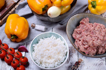 Boiled rice, raw pork and beef mince and yellow bell peppers. Ingredients for making stuffed peppers