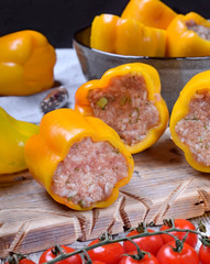Yellow bell peppers stuffed with raw pork and beef mince on the board. Process of making a meal