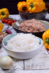 Boiled rice, raw pork and beef mince and yellow bell peppers. Ingredients for making stuffed peppers