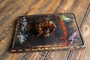 Grilled meat with spices and sauce on a wooden table.	