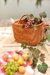 Fototapeta na wymiar Picnic basket wine and fruits with lake view