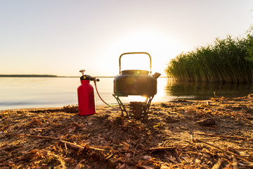 Campingkocher an einem See bei Sonnenuntergang