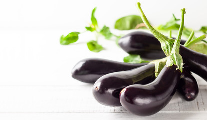 Fresh eggplants on a white wooden table.