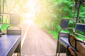 Point of view shot from inside a moving tuk tuk. travel around Asia, Sunny road in the forest.