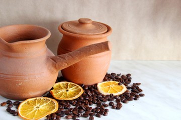 brown clay dishes. Turk and milk jug, made of clay dishes, a lot of roasted coffee bean and dried orange. composition, selective focus