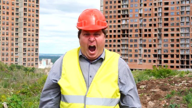 Male builder foreman, worker or architect on construction building site is shouting and looking to camera