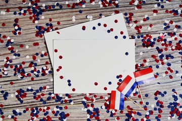 April 30 . mini flags with paper confetti and sheets of white paper. The concept of Netherlands independence Day and national day of the Netherlands.Copy space. mocup, space for text