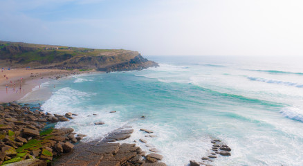 Praia das Maçãs in Portugal - view of a beautiful beach and rocky coastline with large waves on a sunny summer day