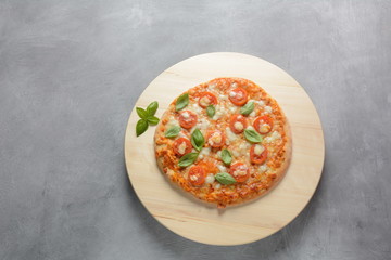 Homemade Italian Neapolitan pizza Margherita with melted mozzarella cheese and tomatoes garnished with fresh basil