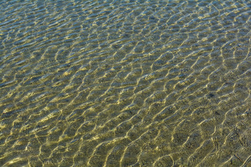 Fototapeta na wymiar Ripples on the surface of the sea water with sun highlights.