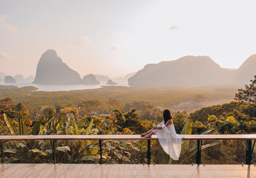 Woman with the white dress sit and see the mountain in early morning at the Sametnangshe Island viewpoint, Phang-Nga, Thailand.