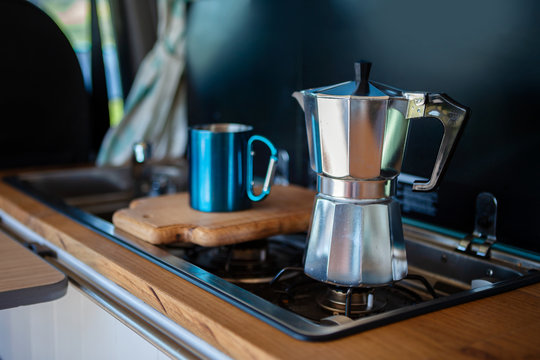 Aqua Bialetti stovetop coffee maker and mug, on a van gas cooker