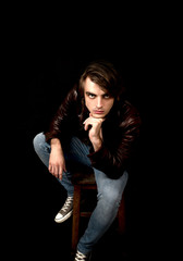 Young man wearing jeans and leather jacket in studio
