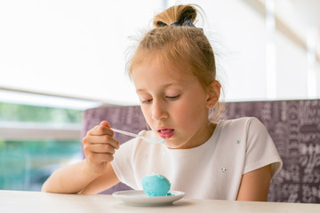 Little girl eating ice cream in a cafe. Adorable little girl eating ice cream at summer. Happy girl eating ice cream in cafe