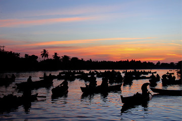 Silhouettes of boats from the "Floating Market" on a river at a colorful sunrise in Borneo, Indonesia.