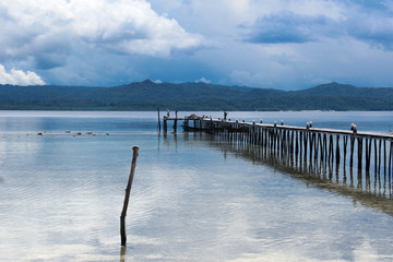 Old traditional wooden jetty over calm water in the ocean near Kri Island, Raja Ampat, south-east Asia.