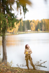 Brunette girl with curls, Golden autumn in the Park by the water, with a thermocup, light brown clothes.