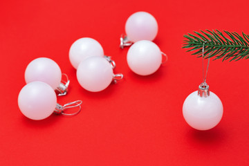 Christmas ball on red paper background. Traditional holiday winter toy hanging on christmas tree branch. Minimal christmas concept.